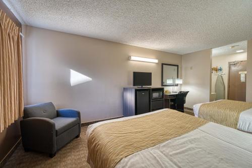 a hotel room with two beds and a chair at Super 8 by Wyndham Sturgis in Sturgis