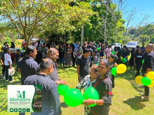 a crowd of people standing in a field with green balloons at Mandara Nature Gardens in Veyangoda