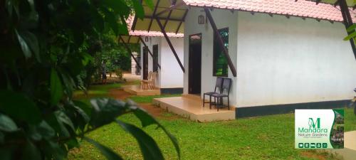 a white building with a chair sitting outside of it at Mandara Nature Gardens in Veyangoda