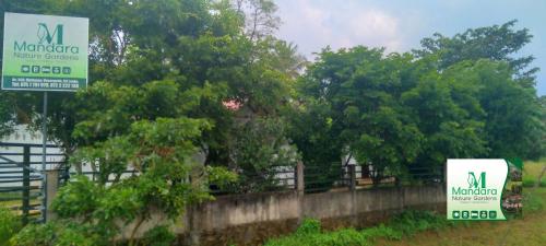two signs in front of a fence with trees at Mandara Nature Gardens in Veyangoda