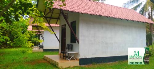 a small white building with a chair in front of it at Mandara Nature Gardens in Veyangoda