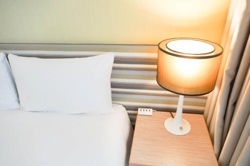 a bedroom with a bed and a lamp on a night stand at 塔木德酒店 台中火車站館 Talmud Hotel Taichung Station in Taichung