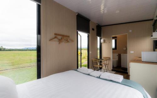 a bedroom with a large bed with a large window at Saffrondreams Farmstay by Tiny Away in West Eyreton