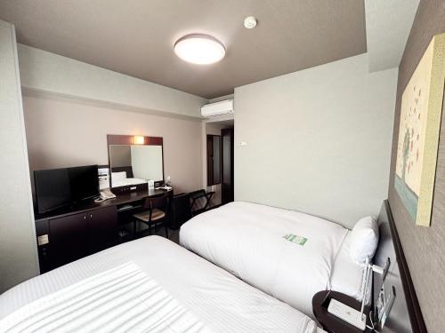a hotel room with two beds and a desk at Hotel Route-Inn Iyo-Saijo in Saijo