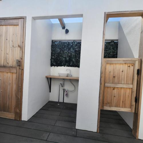 a bathroom with two wooden doors and a sink at 3ベッド3バス ヴィラアパラギ宮古島 in Miyako Island