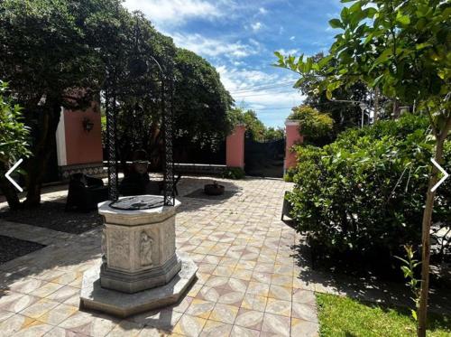 a stone fountain in a courtyard with trees and bushes at Las Flores in San Isidro