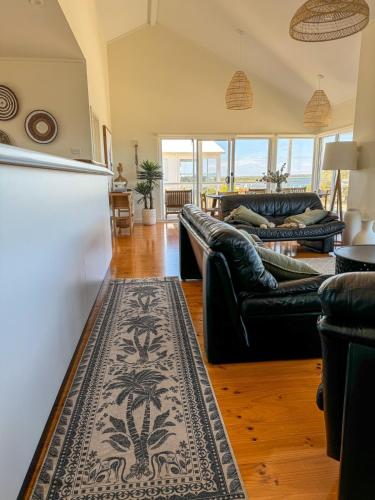 a living room with two couches and a kitchen at Océane Beach House Marion Bay South Australia in Marion Bay