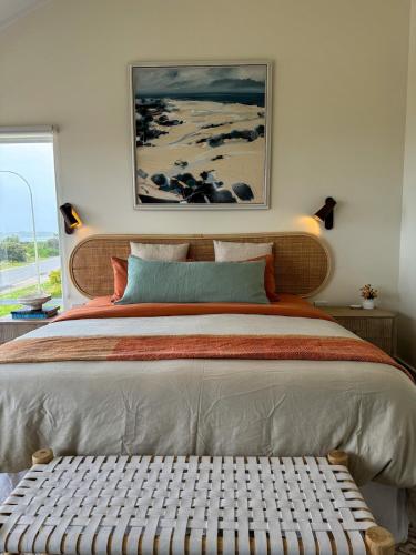 a bedroom with a large bed with a bench in it at Océane Beach House Marion Bay South Australia in Marion Bay