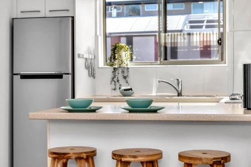 a kitchen with two bowls on a counter with three stools at Somerton Sands - Coastal Living by Glenelg South in Somerton Park