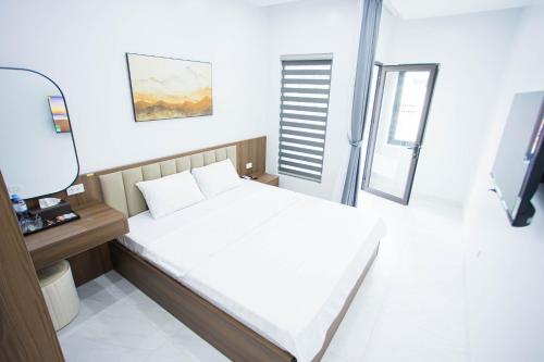 a bedroom with a white bed and a television at Khoai Mật Homestay in Mộc Châu