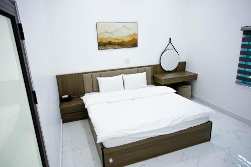 a bedroom with a bed with white sheets and a mirror at Khoai Mật Homestay in Mộc Châu