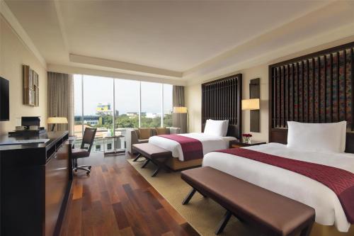 a hotel room with two beds and a large window at Kempinski Hotel Gold Coast City in Accra