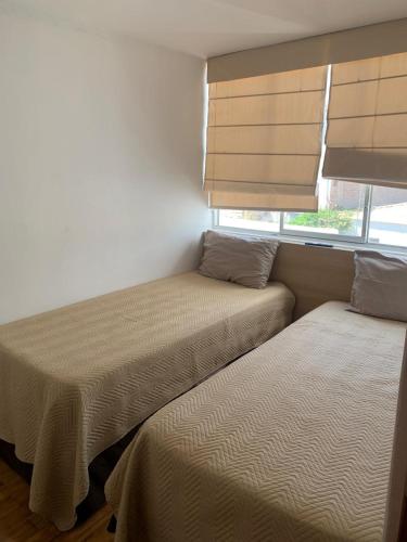 a bedroom with two beds and a window with blinds at Apart Marchelo 2 in San Antonio