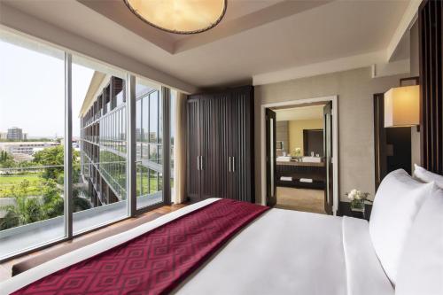 a bedroom with a large bed and a large window at Kempinski Hotel Gold Coast City in Accra