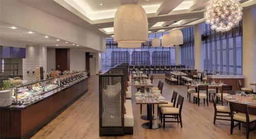 a restaurant with tables and chairs and chandeliers at Kempinski Hotel Gold Coast City in Accra