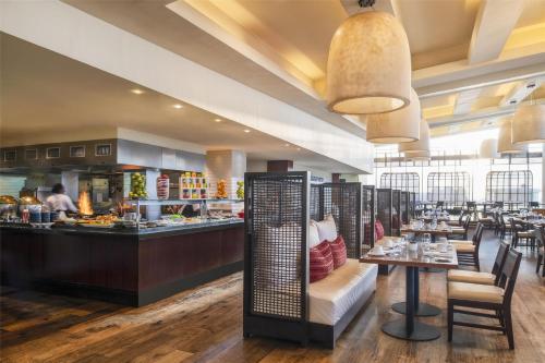 a restaurant with a counter with tables and chairs at Kempinski Hotel Gold Coast City in Accra