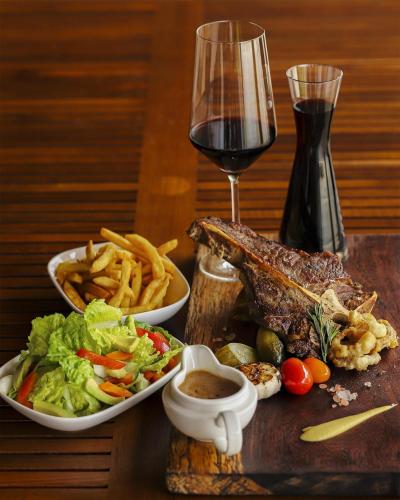 a table with two plates of food and a glass of wine at Kempinski Hotel Gold Coast City in Accra
