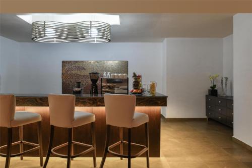 a kitchen with a bar with three stools at Kempinski Hotel Gold Coast City in Accra
