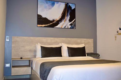 a bedroom with a bed with a picture above it at Rooca Habitat Guatape in Guatapé