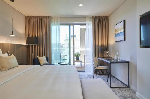 a hotel room with a bed and a desk and a window at Hotel Kempinski Palace Portorož in Portorož