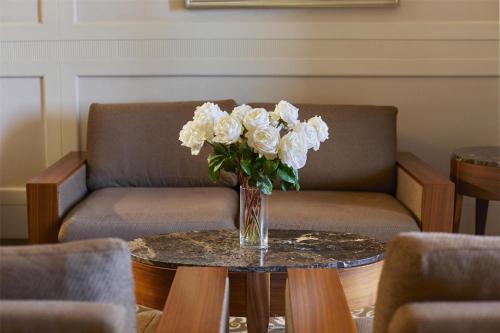 a vase of white roses sitting on a table at Hotel Kempinski Palace Portorož in Portorož