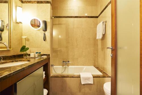 a bathroom with a tub and a sink and a toilet at Hotel Kempinski Palace Portorož in Portorož