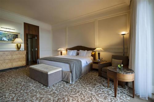 a hotel room with a bed and a chair and a table at Hotel Kempinski Palace Portorož in Portorož