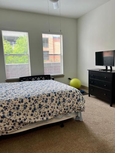 a bedroom with a bed and a tv and two windows at Mi Casa es su Casa in Dallas