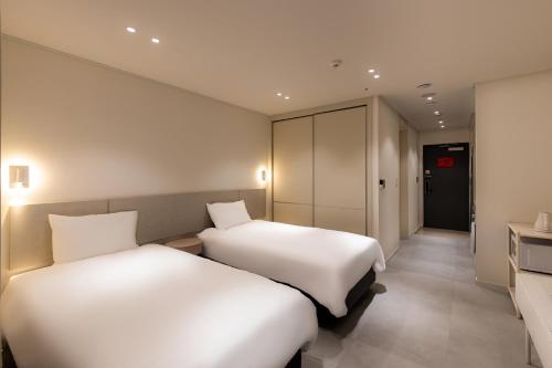 two beds in a hotel room with a corridor at Hotel Modak Namdaemun in Seoul