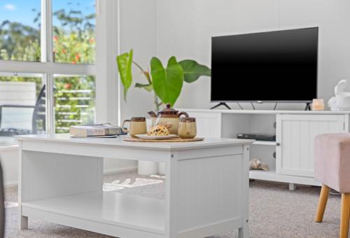 a living room with a white table with a tv at Holiday Haven @ North Haven - club, river, beach in North Haven