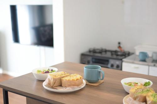a table with two plates of food and a coffee mug at INUYAMA BASE Vacation rental in Inuyama