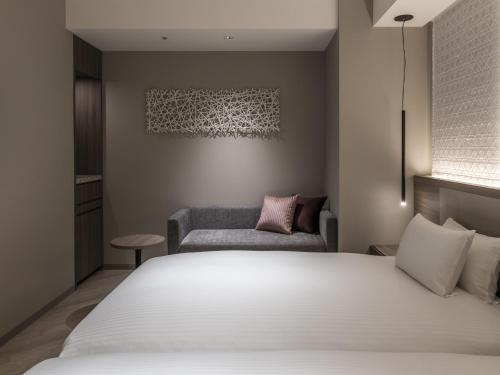 a bedroom with a white bed and a couch at HOTEL FORZA SAPPORO STATION in Sapporo