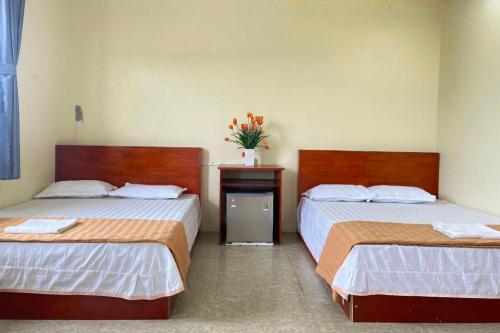 a room with two beds and a vase of flowers at Khách Sạn Thành Trung Vàn Chảy in Quang Ninh