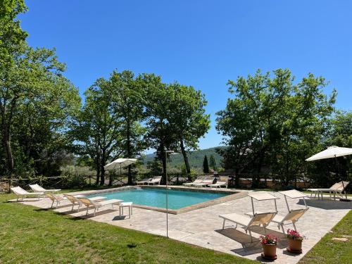 a pool with chairs and umbrellas in a yard at Villa Cresci con piscina in Sassetta