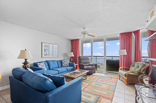 a living room with blue furniture and a balcony at Oceanfront Crescent Shores #208-Sleeps 10 3bed 3bath 28 Foot Balcony in North Myrtle Beach