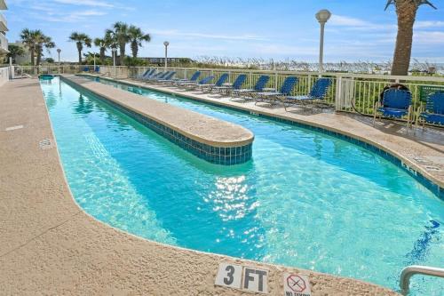 a swimming pool with blue chairs in a resort at Oceanfront Crescent Shores #208-Sleeps 10 3bed 3bath 28 Foot Balcony in North Myrtle Beach