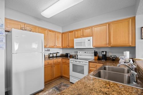 a kitchen with wooden cabinets and a white refrigerator at Oceanfront Crescent Shores #208-Sleeps 10 3bed 3bath 28 Foot Balcony in North Myrtle Beach