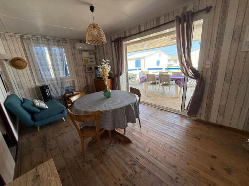 un salon avec une table et des chaises et une salle à manger dans l'établissement Chalet à Gruissan pour 8 pers, confort et charme - FR-1-784-41, à Gruissan