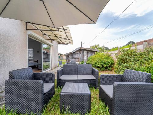 un patio avec des chaises, une table et un parasol dans l'établissement Maison de vacances à Lit-et-Mixe pour 4 pers. - Calme et nature avec jardin inclus - FR-1-50-176, à Lit-et-Mixe