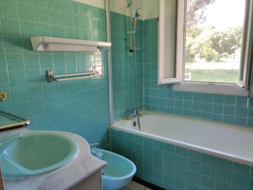 La salle de bains est pourvue de carrelage vert, d'une baignoire et d'un lavabo. dans l'établissement Villa climatisée avec grand jardin, animaux admis - FR-1-776-138, à Palau-del-Vidre
