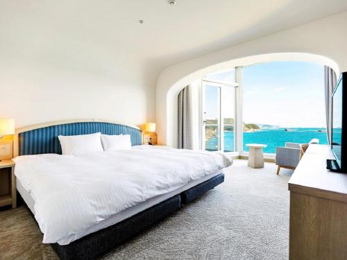 a bedroom with a large bed and a large window at Nichinankaigan Nango Prince Hotel in Nichinan