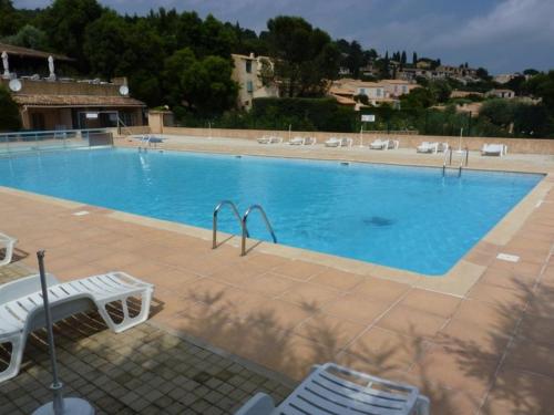 une grande piscine bleue avec des chaises et un bâtiment dans l'établissement Mas 2 chambres avec terrasse et jardin privatif - FR-1-726-61, à La Croix-Valmer