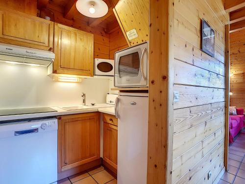 une cuisine avec un réfrigérateur et un micro-ondes dans l'établissement Demi-chalet cosy à La Clusaz pour 6 pers, cheminée, animaux admis, WiFi - FR-1-818-102, à La Clusaz