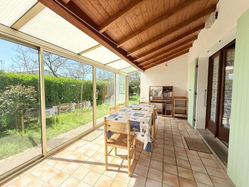 une grande véranda avec une table sur un patio dans l'établissement La Quiétude Oléronaise - Plage à 1.5km - 8 personnes - FR-1-778-49, à Dolus-d'Oléron