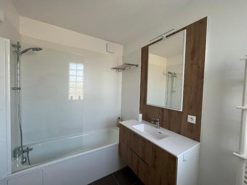 une salle de bain avec un lavabo, une baignoire et un miroir dans l'établissement T2 lumineux en centre-ville avec balcon et parking sécurisé - FR-1-319-612, à La Teste-de-Buch