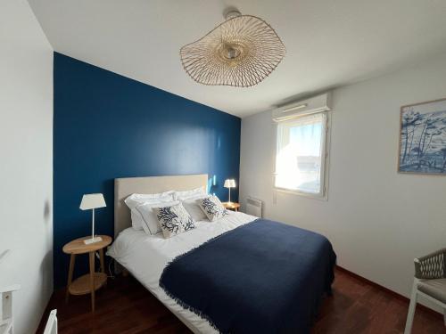 - une chambre avec un mur bleu et un lit dans l'établissement T2 lumineux en centre-ville avec balcon et parking sécurisé - FR-1-319-612, à La Teste-de-Buch