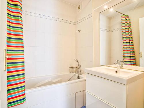 une salle de bain blanche avec une baignoire et un lavabo dans l'établissement Appartement lumineux avec balcon et piscine pour 5 personnes - FR-1-788-67, à Merville-Franceville-Plage
