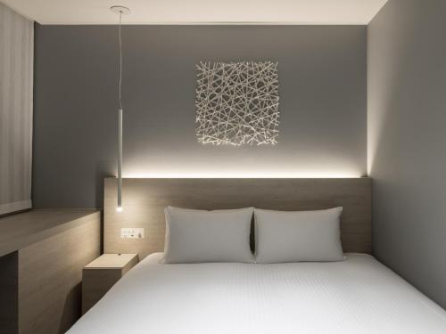 a bedroom with a bed with a light above it at HOTEL FORZA SAPPORO STATION in Sapporo