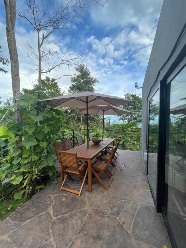 a wooden table with chairs and an umbrella on a patio at Amazon Paradise WiFi Starlink Work or Relax in Morales