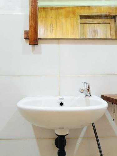 a white sink in a bathroom with a wooden cabinet at Forest Side bungalow in Tetebatu